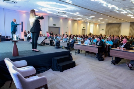 MB Comunica��o Empresarial e Organizacional - O SENAI/SC reuniu especialistas e lideran�as da cadeia de prote�nas no 14� Semin�rio Internacional de Industrializa��o da Carne, realizado em Chapec� (SC) nesta ter�a-feira (18), no Hotel Kindermann. Com programa��o paralela � Mercoagro 2026 � Feira Internacional de Neg�cios, Processamento e Industrializa��o da Carne �, o encontro debateu inova��o, tecnologia e tend�ncias que influenciam a competitividade do setor em um ambiente de mudan�as no mercado global. O coordenador geral da Mercoagro, Nadir Jos� Cervellin, destacou a relev�ncia da pesquisa estar ligada a ind�stria e que a feira possui tr�s pilares: neg�cios, relacionamento e conhecimento. �Quando a pesquisa caminha junto com a ind�stria, ela vira resultado, vira competitividade e vira solu��o aplicada no dia a dia das empresas. A Mercoagro nasceu com esse prop�sito e segue fiel a ele. Por isso, trabalhamos para que a feira seja um ambiente completo: um espa�o para gerar neg�cios, fortalecer conex�es e, principalmente, compartilhar conhecimento que prepara o setor para os pr�ximos desafios�, afirmou. O diretor-regional do SENAI e diretor de Gest�o de Mercado, Fabrizio Pereira, abordou a pujan�a do setor de alimentos na regi�o oeste de Santa Catarina e os servi�os que a FIESC oferece para fortalecer a ind�stria. �Para se ter uma ideia, cerca de 33% de tudo o que � produzido no estado acontece nesse eixo que vai de Joa�aba at� a fronteira. � algo realmente expressivo. Mesmo diante dos desafios log�sticos que a regi�o enfrenta h� anos, a for�a, a compet�ncia e a qualidade das pessoas fazem toda a diferen�a�. GEOPOL�TICA NO MERCADO DE CARNES Para abrir o cronograma de palestras, o diretor executivo do Sindicarne, Jorge Luiz de Lima, apresentou os impactos da geopol�tica no mercado de carnes. Para dimensionar a relev�ncia do setor, ele apresentou alguns n�meros: embora o estado tenha pouco mais de 1% do territ�rio nacional, lidera a produ��o e exporta��o de carne su�na no Brasil e ocupa a segunda posi��o na produ��o de frango, atr�s apenas do Paran�. Junto com Paran� e Rio Grande do Sul, Santa Catarina concentra 75% da produ��o nacional de frango e 85% da produ��o de su�nos, evidenciando a for�a da regi�o Sul nesse segmento. Jorge pontuou a dimens�o da cadeia produtiva no estado de Santa Catarina. �As grandes agroind�strias empregam cerca de 60 mil pessoas diretamente, mas, considerando toda a cadeia, desde pequenos abatedouros at� servi�os indiretos, o n�mero chega a 124 mil empregos. Al�m disso, esses postos diretos geram aproximadamente 480 mil empregos indiretos, envolvendo atividades como transporte, log�stica e fornecimento de insumos�. Para ilustrar a dimens�o log�stica do setor, Lima destacou que uma �nica planta produtiva com capacidade para 200 mil aves ou 5 mil su�nos por dia pode gerar uma movimenta��o di�ria de cerca de 5.240 viagens de caminh�es. �A complexidade log�stica tamb�m se reflete no trabalho de campo, pois cada motorista percorre, em m�dia, 3 mil quil�metros por m�s, e o setor conta com cerca de 1.200 profissionais nessa fun��o. No transporte internacional, s�o movimentados cerca de 90 mil cont�ineres por ano uma m�dia de 344 por dia com aproximadamente 167 caminh�es circulando diariamente entre o Oeste e os portos do litoral. Esse volume gera custos expressivos. O transporte de cargas representa uma despesa anual de cerca de R$ 3 bilh�es, enquanto os custos portu�rios somam aproximadamente R$ 50 milh�es�. De acordo com Lima os conflitos geopol�ticos internacionais t�m impacto direto sobre o setor. Ele citou, principalmente, a guerra entre R�ssia e Ucr�nia e as tens�es no Oriente M�dio, como o conflito envolvendo o Ir�. Antes de abordar os efeitos de mercado, ressaltou que qualquer conflito b�lico representa uma trag�dia humana embora, inevitavelmente, tamb�m traga consequ�ncias econ�micas. �Santa Catarina exporta para mais de 150 destinos, com mercados relevantes como Jap�o, China, Filipinas, Emirados �rabes Unidos, Ar�bia Saudita, Reino Unido e pa�ses europeus. Essa ampla presen�a internacional faz com que o setor seja altamente sens�vel a mudan�as geopol�ticas. No caso da guerra entre R�ssia e Ucr�nia, o impacto foi imediato, especialmente no custo dos insumos. A Ucr�nia � um dos maiores produtores de milho do mundo, e, com o in�cio do conflito, o pre�o do gr�o disparou, chegando a cerca de R$ 113 por saca em Chapec�. Atualmente, o valor se estabilizou em torno de R$ 67, com varia��es recentes influenciadas por novos conflitos�, concluiu. ALTO VALOR AGREGADO O pesquisador da AgResearch Ltd, Dr. Mustafa Farouk, veio da Nova Zel�ndia para o semin�rio e palestrou sobre o desenvolvimento de produtos c�rneos com alto valor agregado. Ao abordar a gera��o de valor na ind�stria da carne, Farouk destacou tr�s pontos centrais. O primeiro � que, independentemente do perfil do consumidor h� uma pergunta essencial que orienta as escolhas de consumo: �como aquele alimento impacta sua sa�de f�sica e mental ao longo da vida?�. O segundo ponto � o potencial ainda n�o totalmente explorado da carca�a. Segundo o pesquisador, seja na carne bovina, su�na ou de outras esp�cies, ainda h� espa�o para extrair mais valor a partir de cada animal e ampliar o aproveitamento de seus componentes. J� o terceiro aspecto aponta para uma mudan�a de l�gica: n�o � mais poss�vel agregar valor apenas aumentando a produ��o ou aproveitando ao m�ximo a mat�ria prima. O verdadeiro ganho, daqui para frente, est� em compreender melhor o consumidor e suas demandas. �O valor n�o est� mais em produzir mais, mas em produzir melhor para quem vai consumir�, resumiu. Para Farouk, o desafio est� na forma de apresentar os produtos ao consumidor. Cortes como f�gado, cora��o e rins enfrentam resist�ncia quando oferecidos de forma tradicional. �No entanto, quando incorporados a novos formatos como produtos processados ou combinados com outros ingredientes, podem ganhar aceita��o e abrir novas oportunidades de mercado. N�o se trata apenas do que temos, mas de como entregamos isso ao consumidor�. QUALIDADE DA CARNE O professor Dr. M�rcio Duarte, da University of Guelph e da Universidade Federal de Vi�osa, discutiu a influ�ncia da suplementa��o na qualidade da carne, relacionando manejo, nutri��o e atributos finais do produto. Ao abordar os fatores que determinam a qualidade da carne, o palestrante explicou que � essencial compreender a diferen�a entre m�sculo e carne. �A carne, como produto final, � resultado da transforma��o do tecido muscular, e s�o as c�lulas presentes nesse tecido que determinam atributos como maciez, sucul�ncia e valor agregado�. Duarte defendeu a necessidade de compreender toda a din�mica de crescimento, desde a concep��o at� o abate. Um animal abatido aos 21 meses, por exemplo, j� carrega influ�ncias de todo o seu desenvolvimento, iniciado ainda no per�odo gestacional. �A qualidade da carne n�o se constr�i apenas no final do processo, mas ao longo de toda a vida do animal�, sintetizou. O palestrante explicou que, ainda no �tero materno, ocorre a forma��o dos principais tecidos que dar�o origem � carne. Esses tecidos t�m uma origem comum, a partir de um conjunto limitado de c�lulas, cuja maior capacidade de multiplica��o est� concentrada nas fases iniciais do desenvolvimento. Ap�s os primeiros meses de vida, especialmente depois dos sete meses, essa capacidade de prolifera��o celular diminui significativamente. Isso significa que o animal passa a ter um �estoque� limitado de c�lulas capazes de formar gordura intramuscular, o marmoreio. Na pr�tica, isso explica por que estrat�gias focadas apenas na termina��o nem sempre funcionam. �Voc� pode oferecer uma dieta rica em energia, mas se o animal n�o desenvolveu essas c�lulas antes, ele simplesmente n�o ter� capacidade de formar o tecido que gera valor�, reiterou Duarte. Diante disso, o caminho apontado � antecipar as estrat�gias nutricionais e de manejo, atuar desde as fases iniciais, e at� mesmo durante a gesta��o, para estimular o desenvolvimento dessas estruturas. ALIMENTOS PROCESSADOS O representante da Corbion, Msc. Jo�o Yunes, apresentou tend�ncias de ingredientes naturais e sustent�veis em alimentos processados. Yunes frisou que no Brasil j� produzimos a partir da fermenta��o natural produtos que se mantem na temperatura ambiente, isso, mesmo que acompanhe gera��es � inova��o. No entanto, para ind�stria � preciso pensar como manter alimentos fermentados para as prateleiras do mundo inteiro. Ao aprofundar o tema da conserva��o, o palestrante destacou que a deteriora��o de produtos c�rneos ocorre, basicamente, por dois caminhos: biol�gico e qu�mico. Ao falar sobre inova��o, ele ressaltou que o primeiro limite � regulat�rio. �N�o adianta desenvolver uma solu��o se ela n�o � permitida pela legisla��o�, pontuou e ressaltou que as regras variam entre pa�ses, mas seguem diretrizes semelhantes no mundo todo. Entre os principais conservantes utilizados na ind�stria de carnes, destacam-se os �cidos org�nicos e seus derivados, respons�veis por grande parte das aplica��es. O �cido l�tico, por exemplo, origina o lactato, amplamente utilizado no Brasil, especialmente em produtos armazenados em temperatura ambiente. J� o �cido ac�tico d� origem aos acetatos, que atuam de forma complementar, especialmente no controle de microrganismos como a Listeria. Outros compostos incluem os propionatos, com a��o antif�ngica, e os sorbatos, que tamb�m t�m aplica��o na conserva��o de alimentos, dependendo da legisla��o local. Segundo Yunes, o sucesso na conserva��o est� na combina��o adequada desses compostos. �Os conservantes atuam de forma sin�rgica. Quando combinamos corretamente, conseguimos aumentar o shelf life e garantir a seguran�a alimentar�, explicou. INTELIG�NCIA ARTIFICIAL O professor Dr. Jo�o Dorea, da University of Wisconsin, abordou o emprego de intelig�ncia artificial na preven��o da qualidade da carne. O foco do trabalho est� em integrar dados para tornar a tomada de decis�o mais precisa e menos subjetiva. �A ideia � usar intelig�ncia artificial para monitorar o animal e combinar essas informa��es com outros dados, gerando uma gest�o mais eficiente�, explicou. Inicialmente aplicadas dentro das fazendas, agora essas tecnologias come�am a avan�ar tamb�m para a ind�stria, sendo utilizadas no monitoramento de processos ap�s a sa�da da porteira. O uso de c�meras, por exemplo, permite acompanhar o comportamento dos animais em larga escala, analisar aspectos como movimenta��o, postura e poss�veis problemas de locomo��o. Sistemas de vis�o computacional conseguem identificar padr�es, como a curvatura da coluna ou o posicionamento das articula��es o que indica precocemente altera��es na sa�de do animal. Essas mesmas tecnologias podem ser aplicadas na ind�stria para avaliar carca�as e contribuir para an�lises de qualidade da carne. Dorea explicou a intelig�ncia artificial que desenvolveu para solucionar um desafio pr�tico da ind�stria da carne: a falta de padroniza��o dos cortes, especialmente em animais mesti�os. Utilizando ultrassom, imagens 3D e modelos computacionais, a equipe conseguiu prever ainda no animal vivo caracter�sticas como �rea e formato do ribeye, corte bastante valorizado comercialmente. Segundo ele, os resultados mostraram que a tecnologia consegue identificar padr�es que an�lises biom�tricas tradicionais, como peso e comprimento do animal, n�o conseguem captar com a mesma precis�o. A pesquisa avan�ou tamb�m para a predi��o da maciez da carne a partir de imagens simples, inclusive feitas com c�mera de celular. Em parceria com outros pesquisadores, foi desenvolvido um modelo capaz de estimar esse atributo, que normalmente � dif�cil de ser percebido at� por especialistas apenas pela apar�ncia do bife. Para o pesquisador, esse tipo de ferramenta pode trazer ganhos tanto para a ind�stria, ao aumentar a previsibilidade e a padroniza��o dos produtos, quanto para o consumidor, que poder� fazer escolhas mais conscientes com base em informa��es mais confi�veis sobre a qualidade da carne. O semin�rio foi encerrado com o painel �Tend�ncias, desafios e perspectivas para o futuro da ind�stria da carne�, que reuniu o presidente da Aurora Coop, Neivor Canton, o gerente executivo do Sindicarne, Jorge Luiz de Lima, o diretor vice-presidente de Agro e Qualidade da MBRF, Fabio Duarte Stumpf, e o coordenador geral da Mercoagro, Nadir Jos� Cervelin. A discuss�o abordou os caminhos para manter a competitividade do setor diante de um mercado global mais exigente, com destaque para inova��o aplicada, qualidade e efici�ncia ao longo da cadeia produtiva, al�m da import�ncia de integrar pesquisa e ind�stria para transformar conhecimento em resultados e oportunidades de neg�cios.